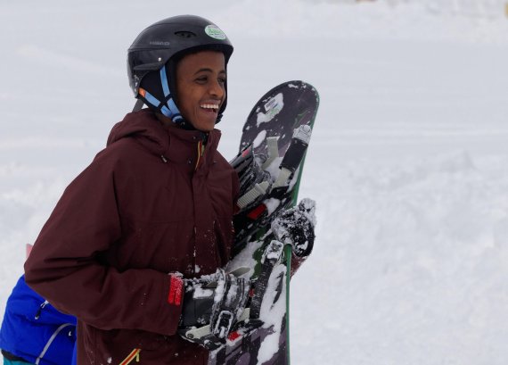mb-schneesporttag A refugee holding a snowboard and looking happy