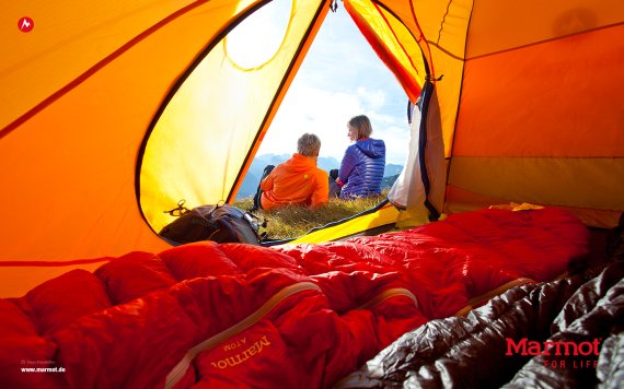 mb-marmot_ispo Ein Ehepaar sitzt vor einem Zelt.