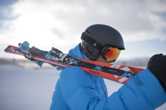 mb-atomic_ispo Ein Wintersportler trägt Ski über der Schulter.