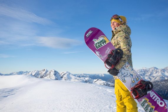 Snowboarder Nicola Thost in the mountains with her snowboard