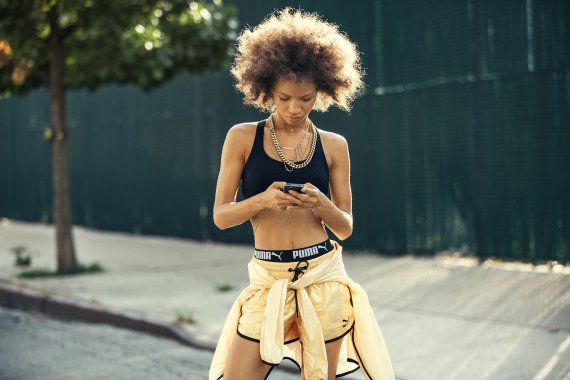 mb-npd-group A woman stands on the street wearing sportswear and looks at her mobile phone.