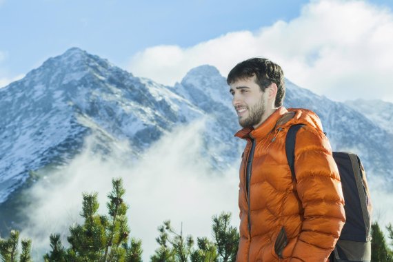 Mann mit Daunenjacke vor Bergpanorama