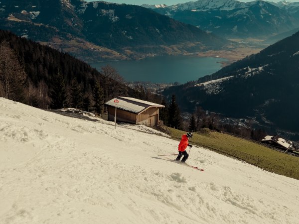 Skifahrer fährt auf künstlich beschneiter Piste bei gutem Wetter