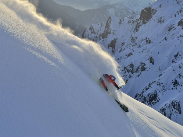 Ein Wintersportler pflügt durch den Schnee an einem steilen Berghang