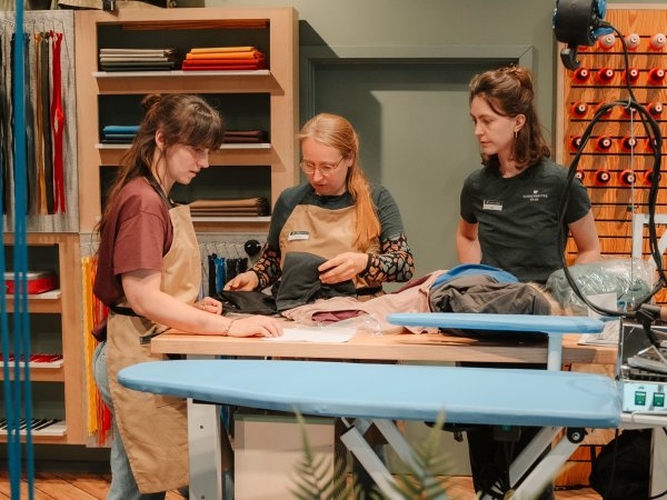 Three women stand in a Globetrotter repair workshop.
