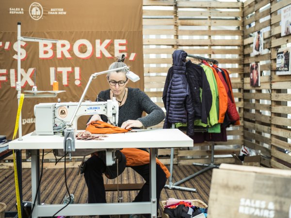 Frau näht orange Winterjacke