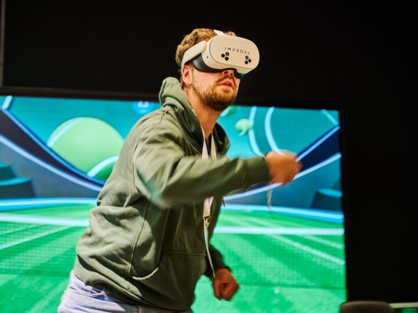 A man wears VR glasses and plays virtual tennis