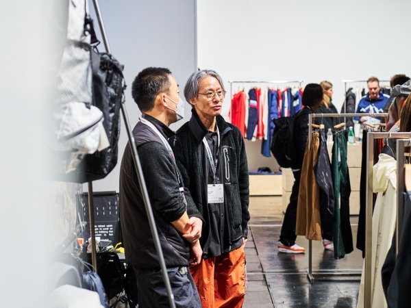 Two men are chatting in a store full of outdoor clothing