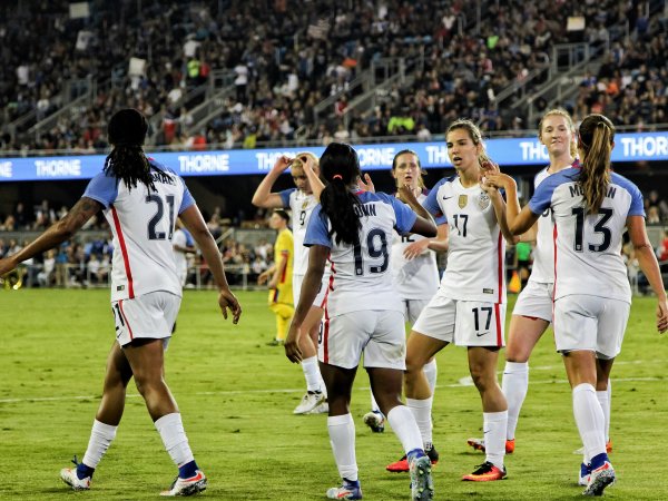 Frauen spielen im Stadion Fußball und klatschen sich ab