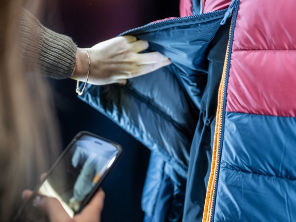 Person looks at colorful outdoor jacket at ISPO 2024