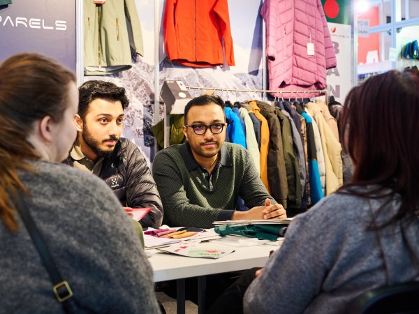 Zwei Retailer und zwei interessierte Kundinnen tauschen sich auf der ISPO 2024 über Outdoor-Themen aus