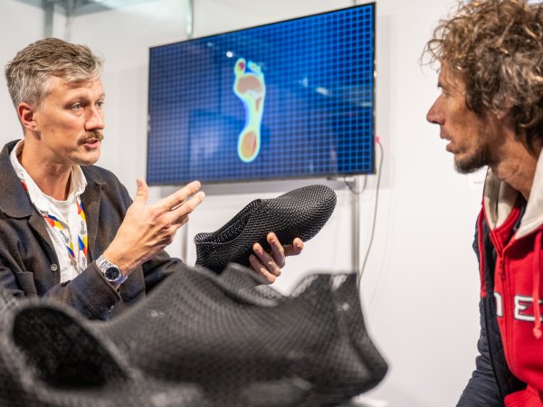 Une personne regarde une veste d'extérieur colorée à l'ISPO 2024