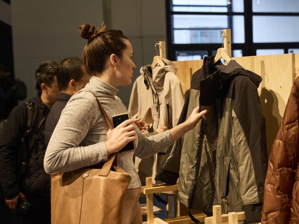 Sport- und Outdoor-begeisterte Besucher auf der ISPO 2024 schauen sich neue, innovative Sportbekleidung an.