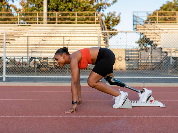 Athletic woman with a prosthetic leg at the start on a running track