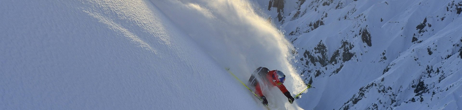 A winter sports enthusiast plows through the snow on a steep mountain slope