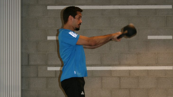Raise the torso slightly and swing the ball between the legs. Simultaneously with the forward movement of the kettlebell, stretch the hips and knees explosively.