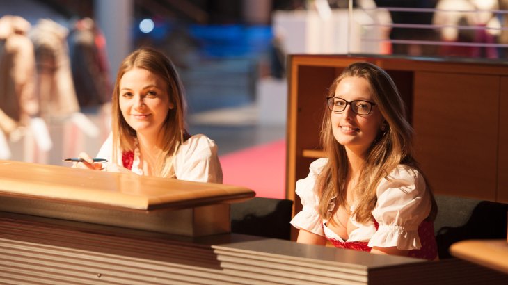 mb-151129-ISPO_Munich_2015_VIPDINNER_jf_0053 Zwei junge Frauen in Dirndln hinter einem Counter.