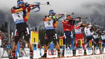Biathletes stand in line and shoot.