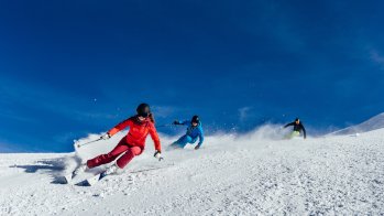 Drei Skifahrer fahren auf der Piste