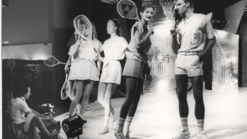 Models führen Tennisbekleidung auf einer Bühne vor.