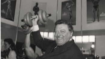 Franz Josef Strauß stemmt eine Hantel in die Luft.