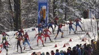 Biathleten fahren einen Berg hinauf.