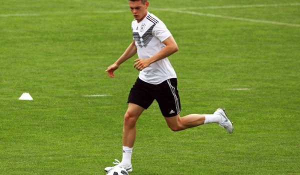 Defender Matthias Ginter naturally looks at the ball on a football field.