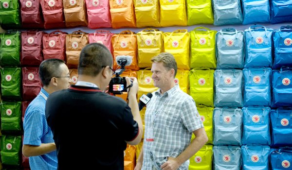 / Fjällraven chooses a more classic approach. Video message in front of the rainbow backpack wall