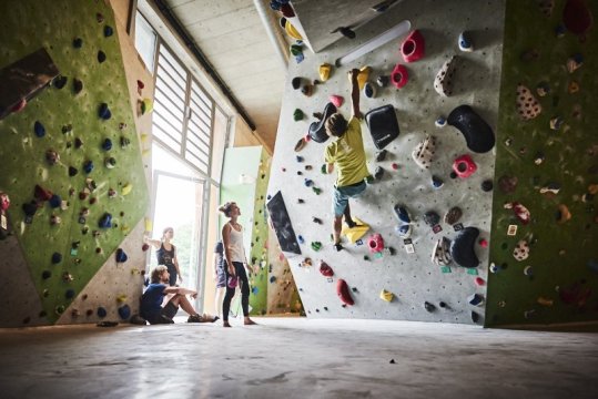 Sportler beim Bouldern an der Kletterwand