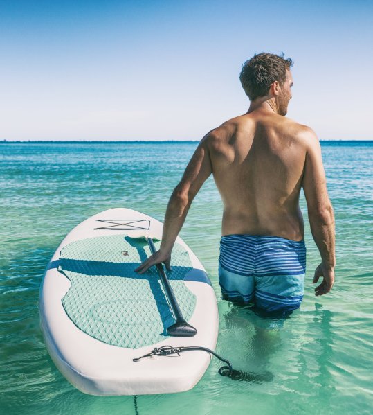 Mann mit Stand Up Paddle Board im Wasser