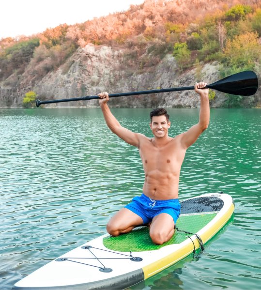 Mann zelebriert seine Fahrt mit dem Stand Up Paddle Board