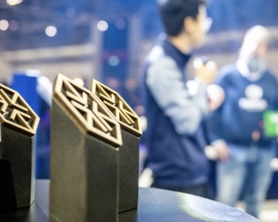 Award Trophäe im Fokus mit Gewinner auf der Bühne im Hintergrund