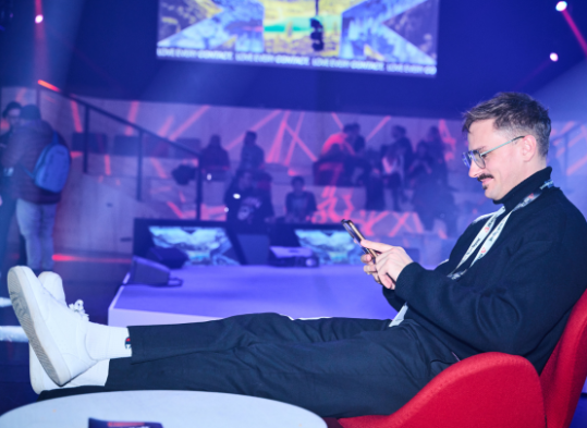 Junger Mann auf der Messe schaut auf sein Handy