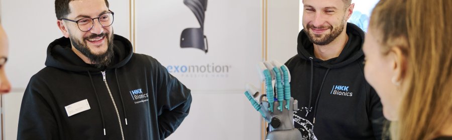 Vier Personen stehen um eine mechanische Hand auf der ISPO