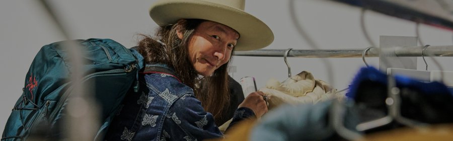 Besucher der ISPO Munich blick durch Kleiderständer in die Kamera