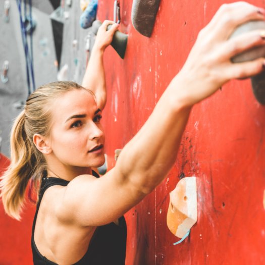 Frau klettert an einer Boulderwand