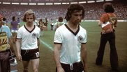WM 1974: Ähnlich wie schon 1966 lief das DFB-Team in schlichten weißen Trikots mit V-Ausschnitt, schwarzem Kragen und schwarzen Ärmelenden auf. Im eigenen Land holten Gerd Müller (r.) und Co. in diesem Outfit den zweiten WM-Titel.