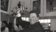 Franz Josef Strauß stemmt eine Hantel in die Luft.
