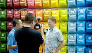 / Fjällraven chooses a more classic approach. Video message in front of the rainbow backpack wall
