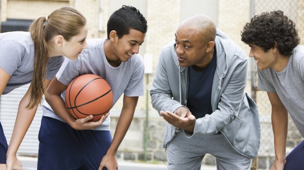 Eine Frau und drei Männer sprechen nach einem Basketballspiel miteinander. 