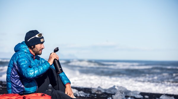 Outdoor-Abenteurer trinkt aus Thermos-Flasche