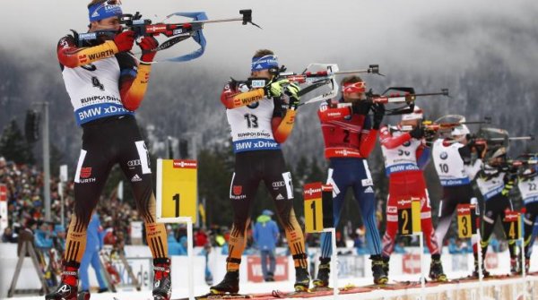 Biathletes stand in line and shoot.