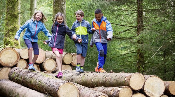Kinder balancieren beim Sport über Baumstämme