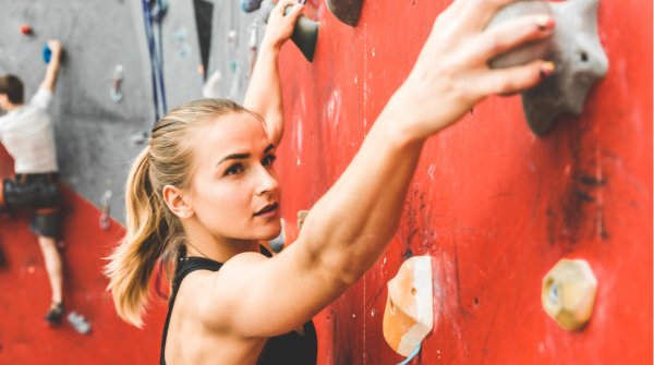 Frau klettert an einer Boulderwand