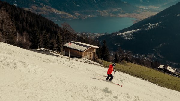 Un skieur skie sur une piste enneigée artificiellement par beau temps