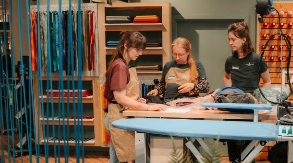 Three women stand in a Globetrotter repair workshop.