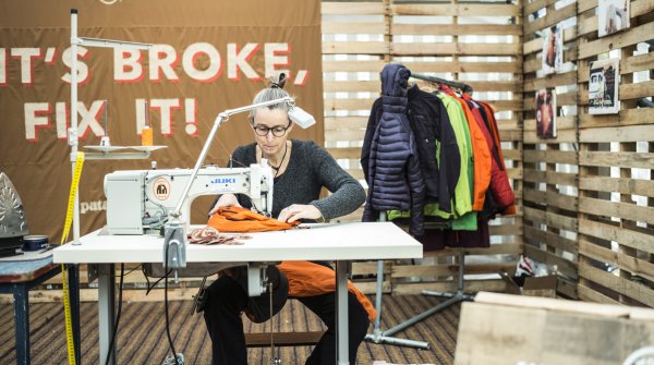Frau näht orange Winterjacke