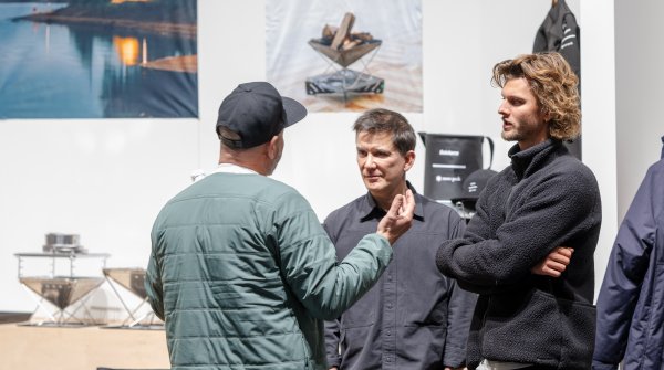 Besucher der ISPO Munich stehen an einem Stand und sprechen miteinander