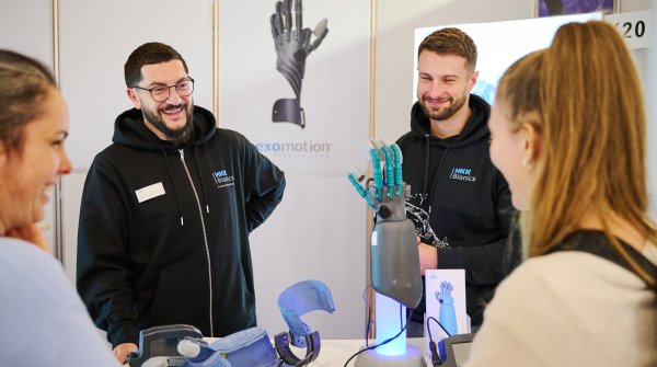 Eine Gruppe Menschen stehen um eine mechanische Hand