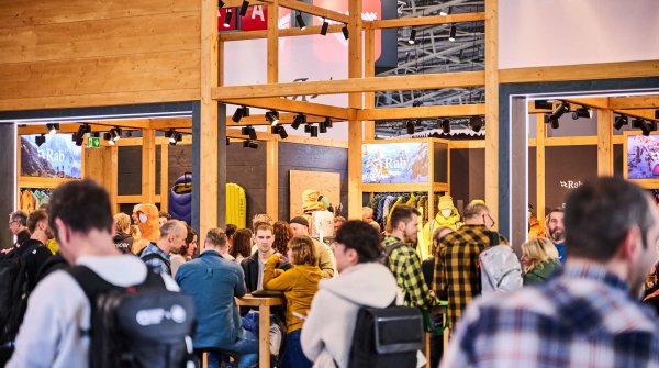 Auf der ISPO MUNICH treffen sich Textilfachhändler in einer schicken Lounge aus Holz an Tischen und unterhalten sich.